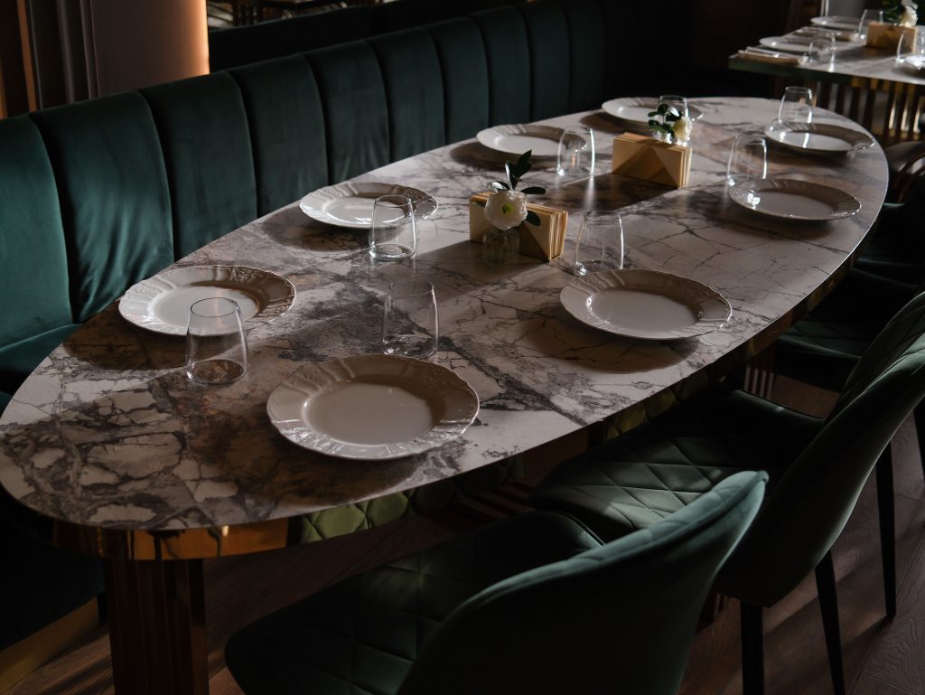 Elegant dining setup with marble table, plates, and glassware in luxury setting.